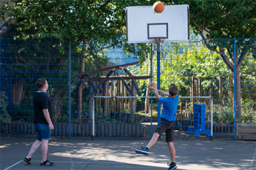 Two young boys playing basketball outside as part of the Avonmouth youth session