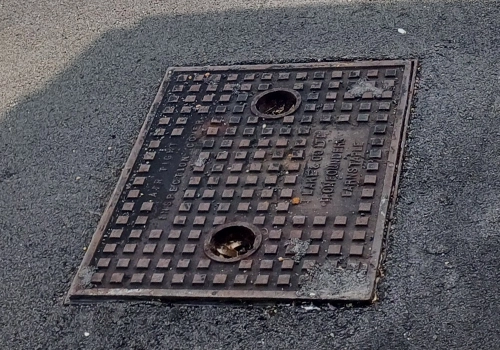 A rectangular metal rapud slide out cover, with raised square detailing and two circular lifting holes. 