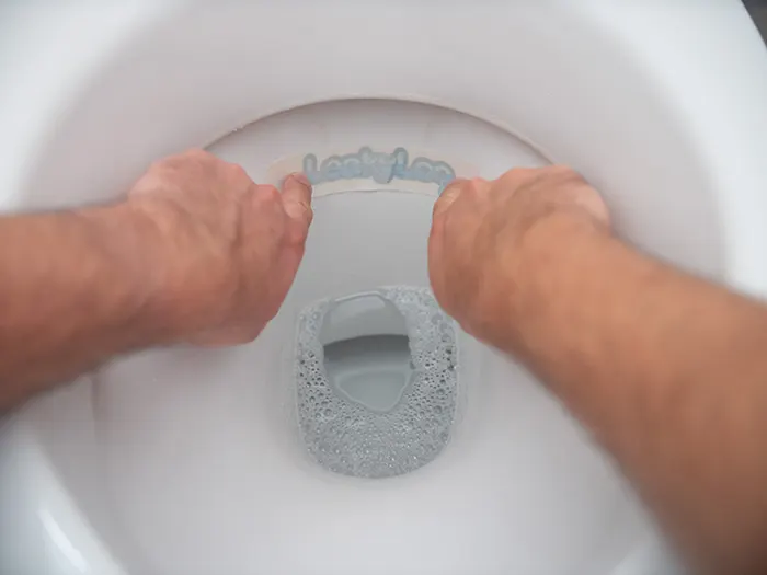 Image of a leaky loo strip being applied to a toilet rim