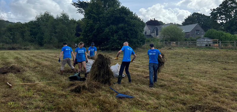Waterforce volunteers clearing cut grass from a field