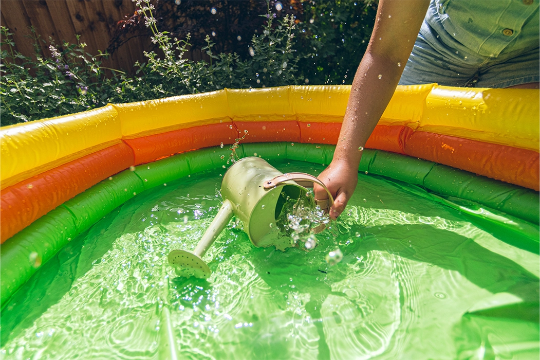 Watering can collecting water from a pool